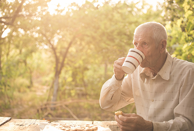 Senior man drinking a tea in his garden adjusting to retirement