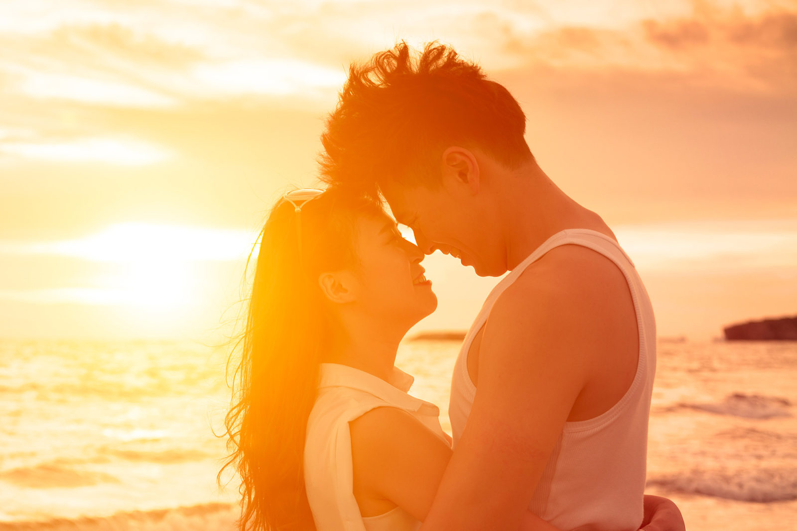 Man and women showing intimacy on a beach with sunset