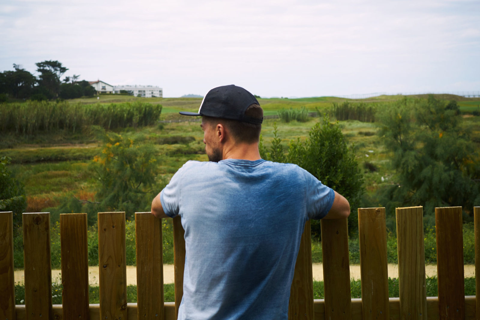 Man leaning against a fence in a field