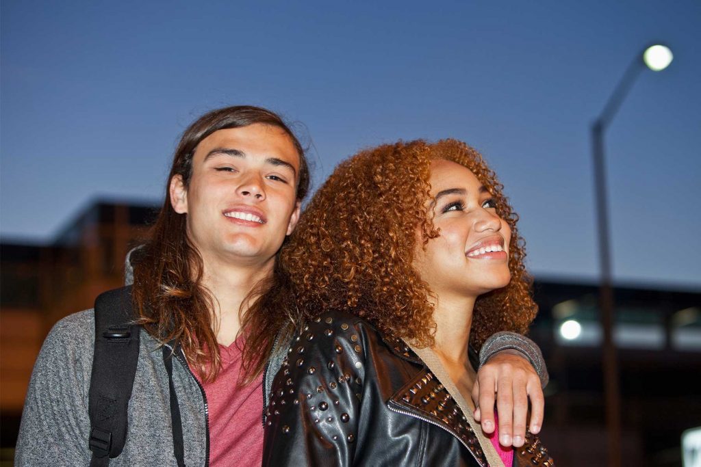 Young couple arm in arm walking at dusk