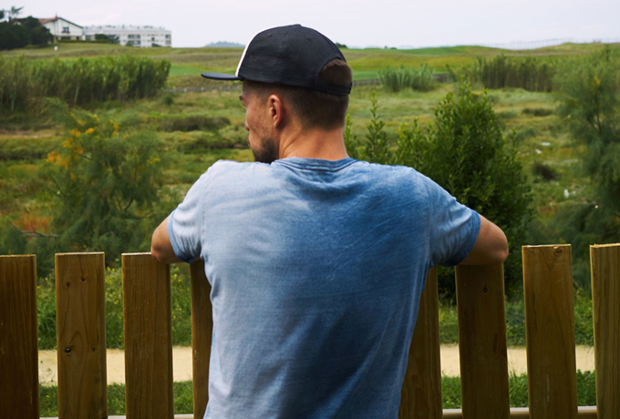Man leaning against a fence in a field